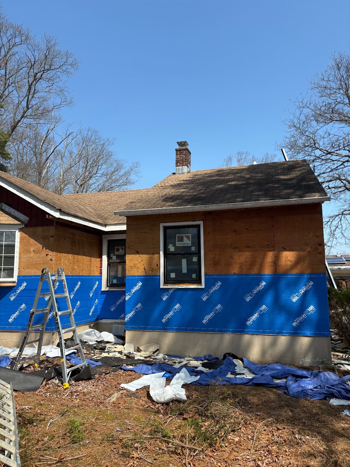 House exterior with old siding removed and weather-resistant barrier installed over the sheathing