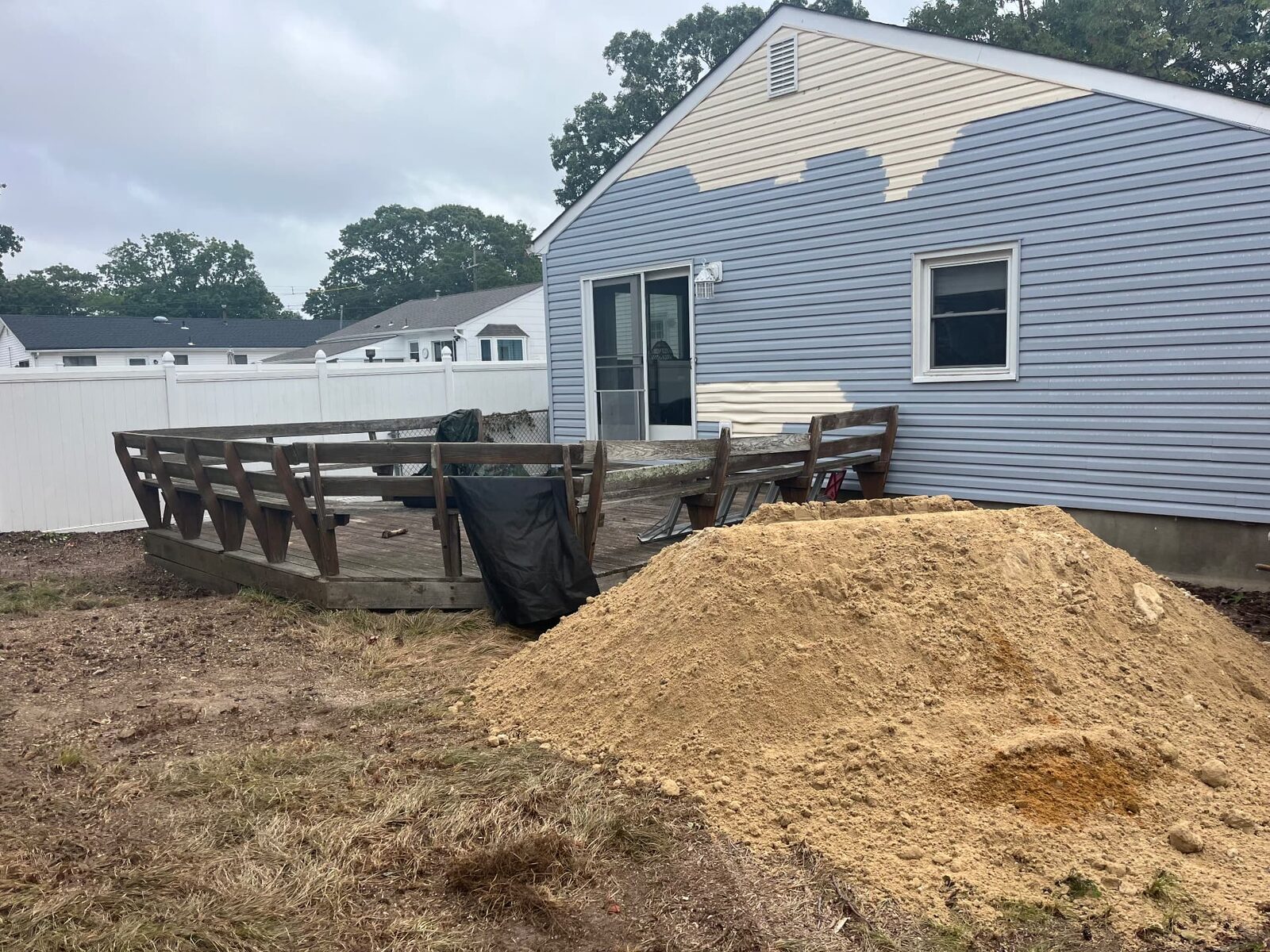 Rear yard with an old deck and a large excavated soil pile during exterior property work