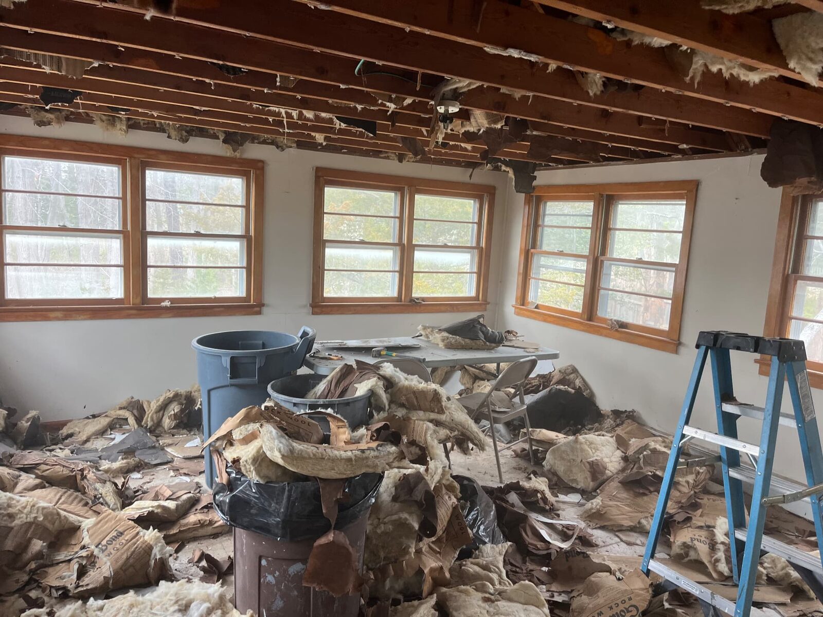 Interior room piled with removed insulation and construction debris during a clear-out