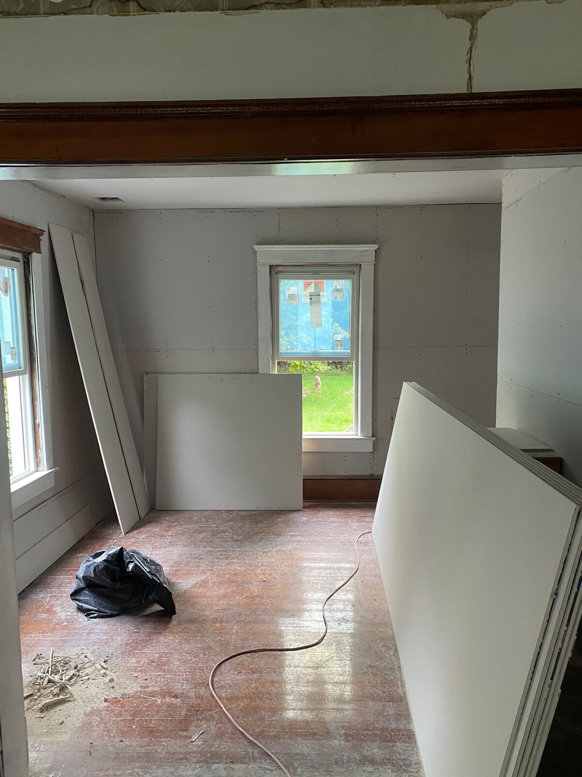 Interior room during renovation with fresh drywall on the walls and boards stacked on the floor