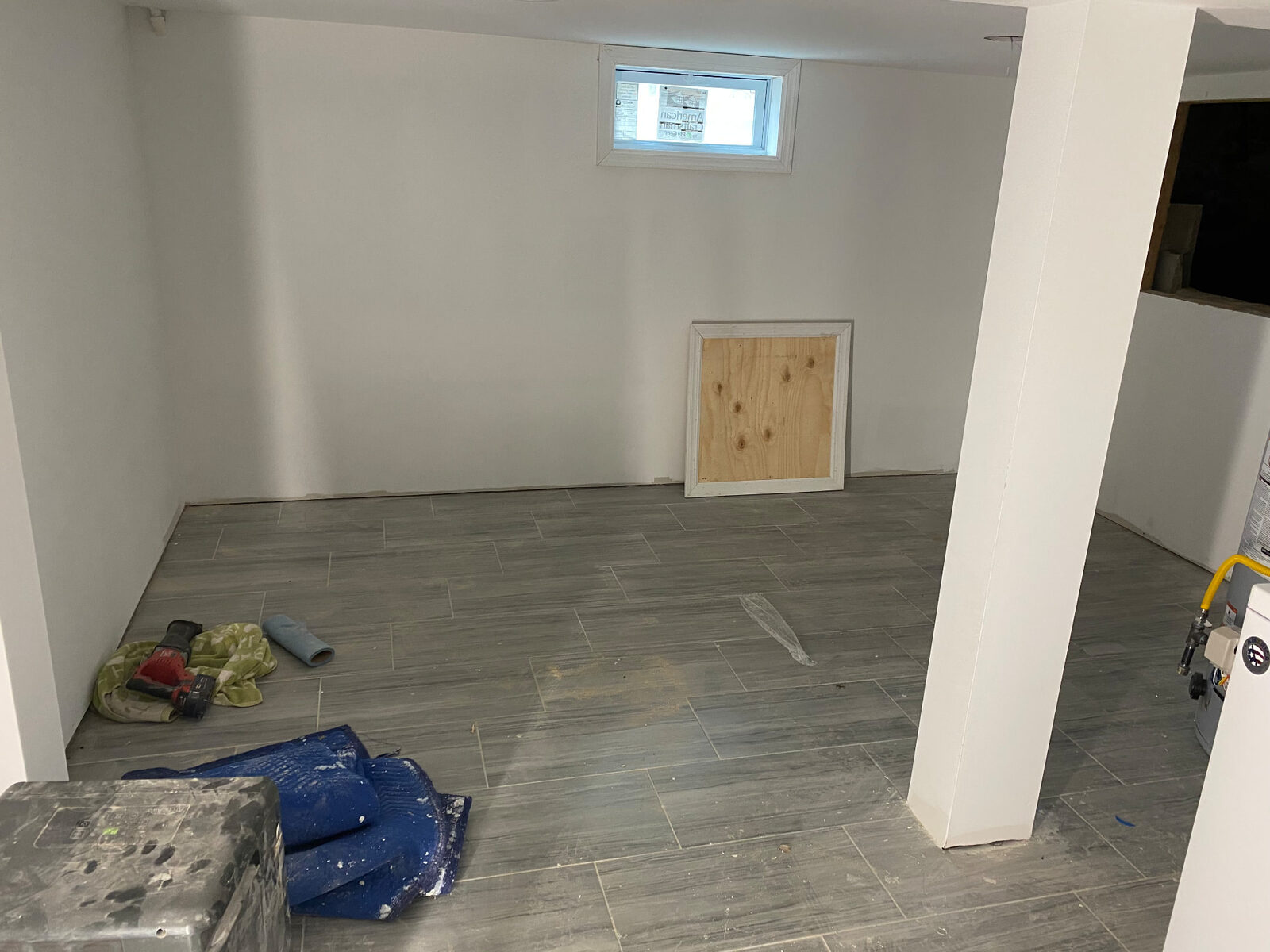 Finished basement living space with wood-look tile flooring and painted white walls