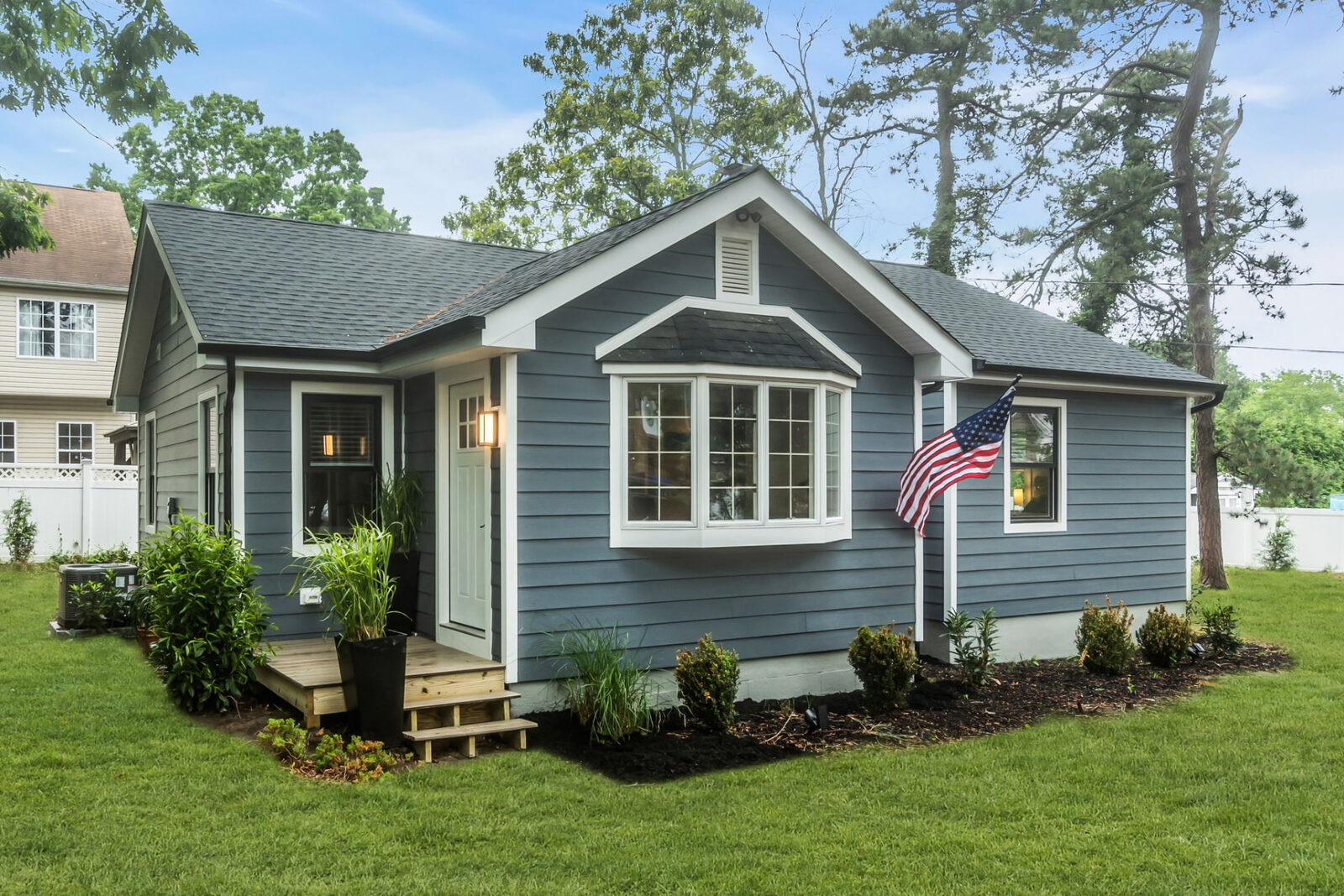 Completed single-story home exterior with new blue siding, white trim, front steps and fresh landscaping