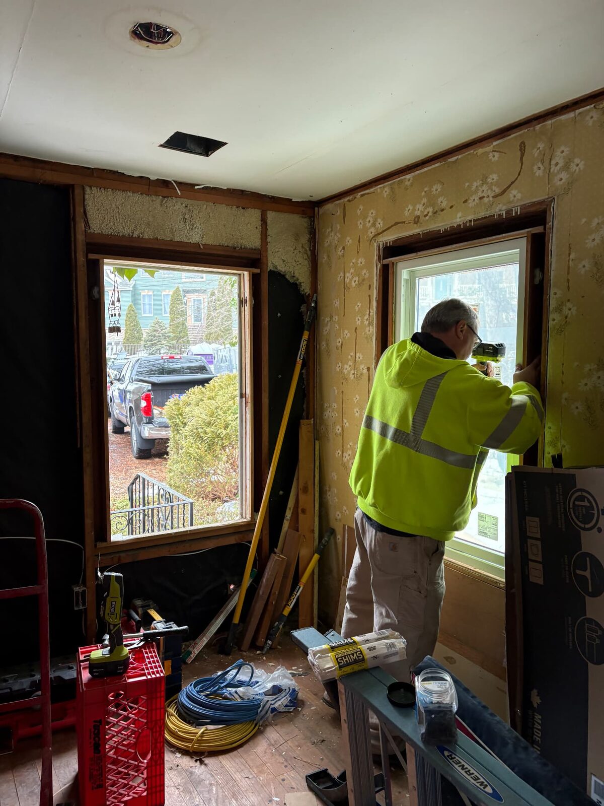 Worker installing a replacement window in a room stripped back during renovation