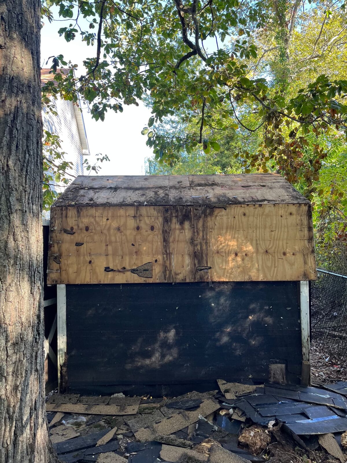 Small outbuilding being demolished with roofing material stripped and stacked on the ground