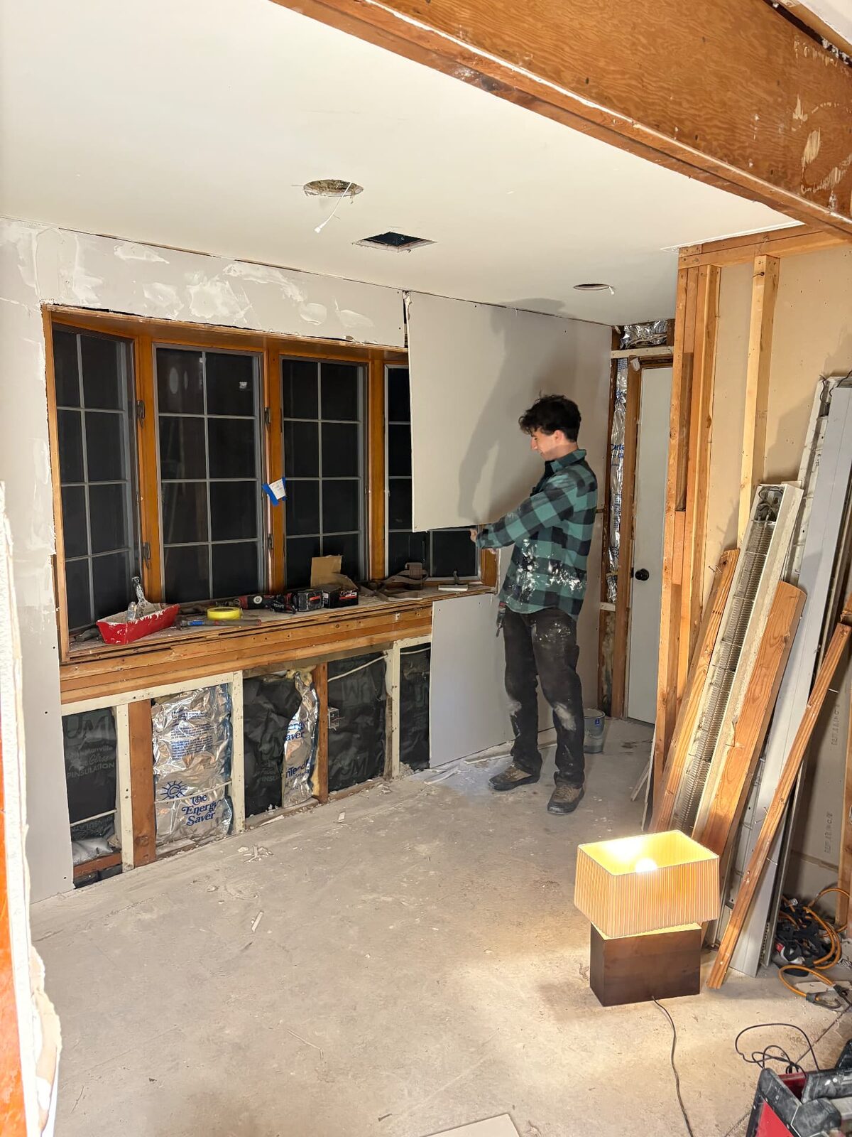 Worker fitting a full sheet of drywall to a wall during an interior renovation