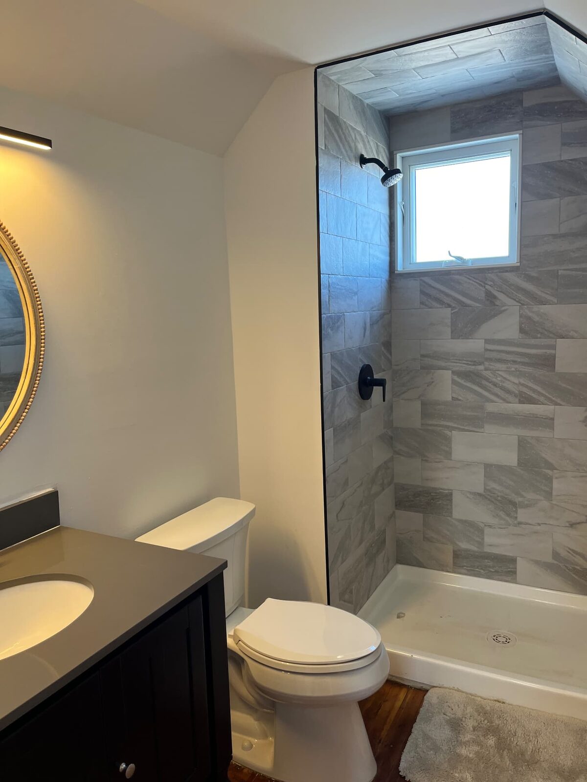 Finished bathroom with a tiled walk-in shower, glass surround, dark wood vanity and new fixtures