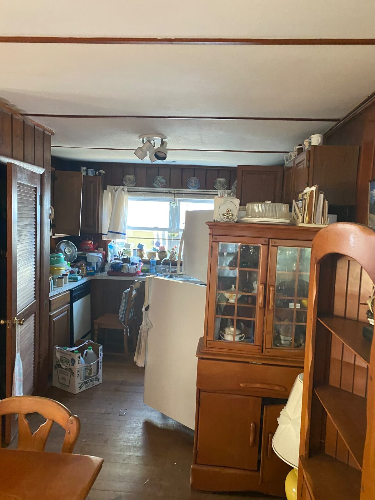 Dated kitchen filled with cabinets, furniture and household contents before a cleanout